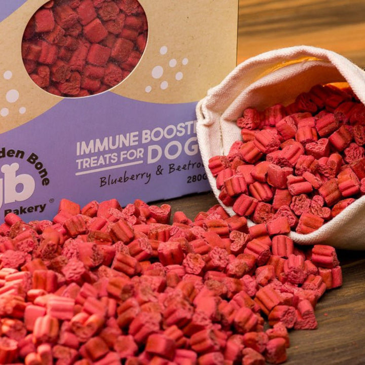 Close up of The Golden Bone Bakery Immune Booster blueberry and beetroot dog treats 280g spilling from linen bag showing oven-baked texture and deep red colour all natural vegan superfood dog treats Australian made